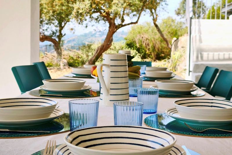 Tavola apparecchiata con ceramiche artigianali e vista sugli ulivi
