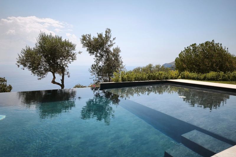 Acqua turchese della piscina a sfioro con l'orizzonte sul mare
