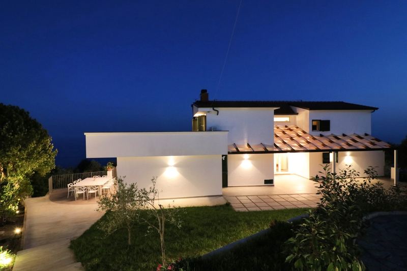 La villa illuminata al crepuscolo con giardino e terrazze