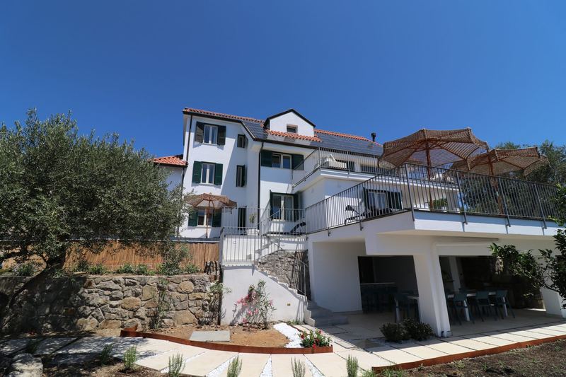 La villa con le sue terrazze, gli ombrelloni e il portico